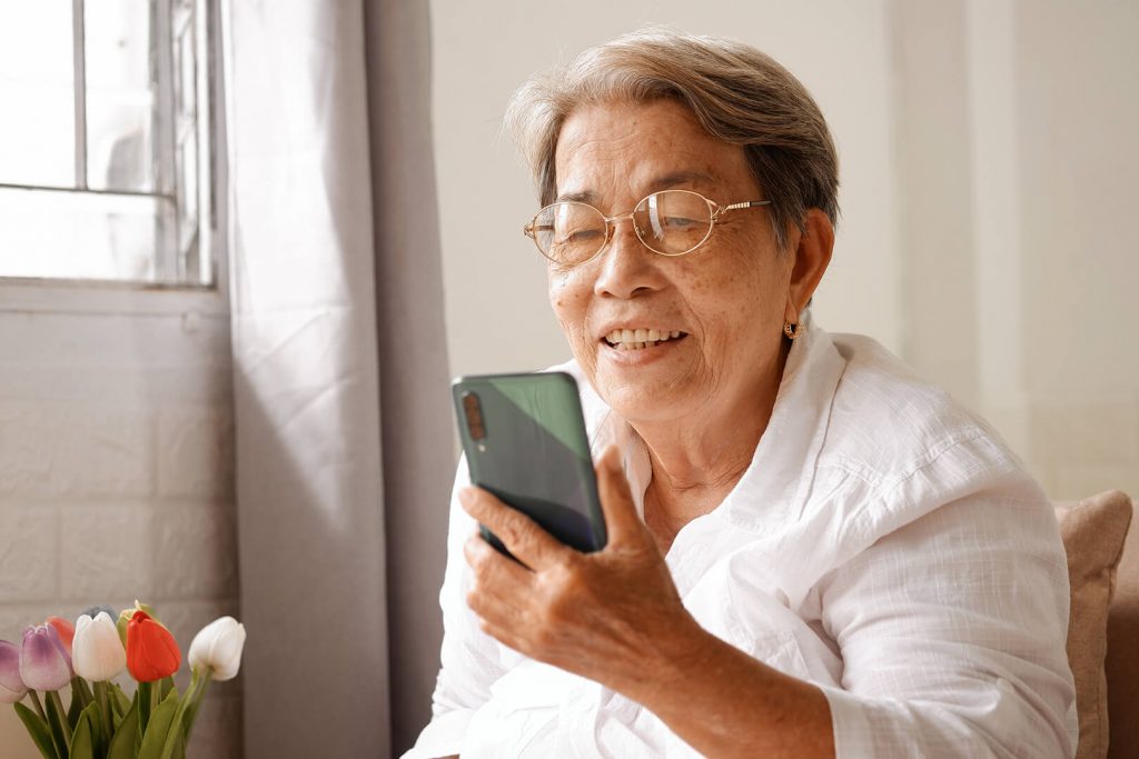 Photo d'une aînée qui semble faire un appel vidéo sur son téléphone intelligent.