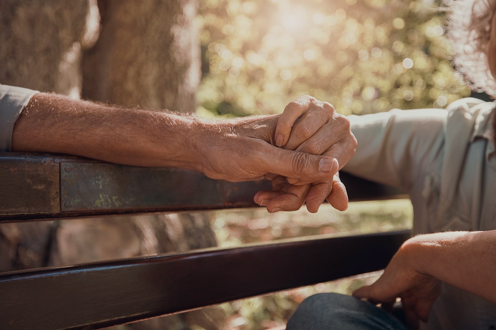 Photo of two seniors holding hands on a park bench.