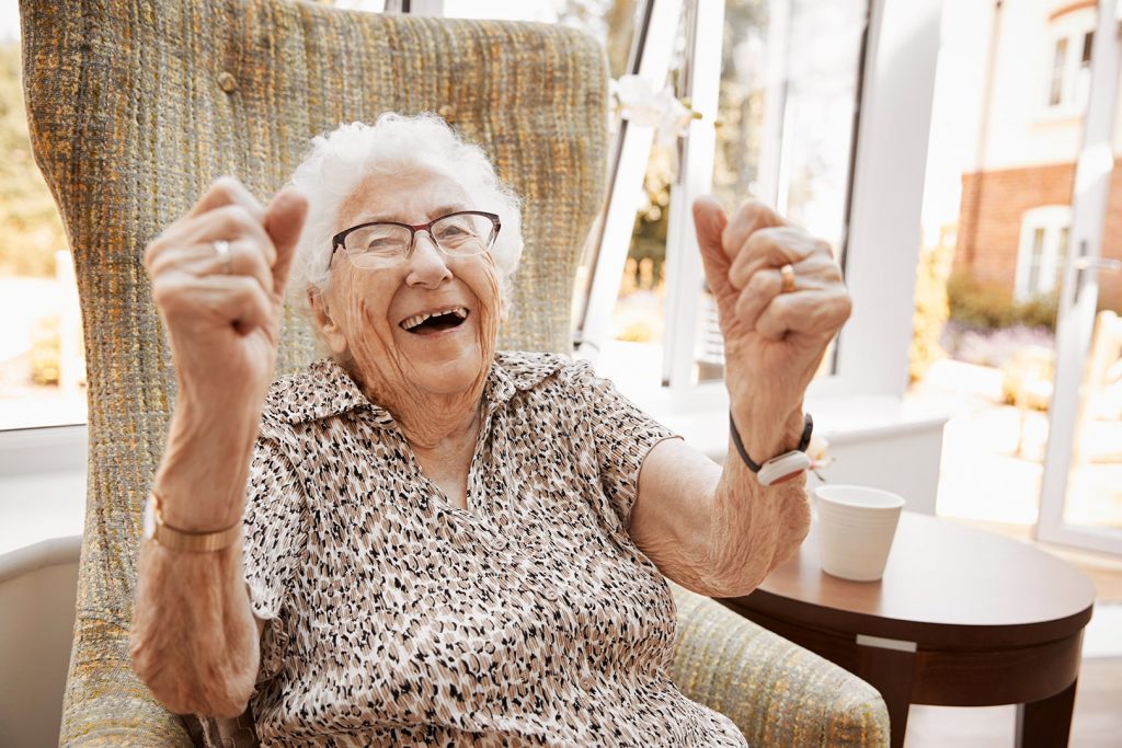Photo d'une aînée qui lève les bras d'enthousiasme.