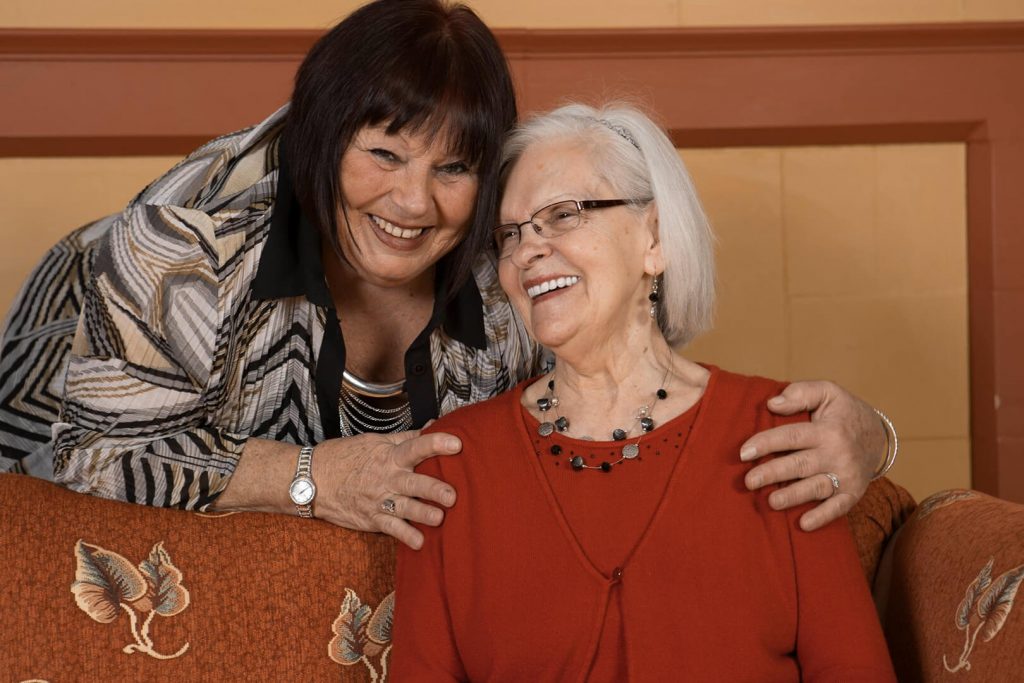 Photo d'une aînée et une bénévole qui sourient ensemble.