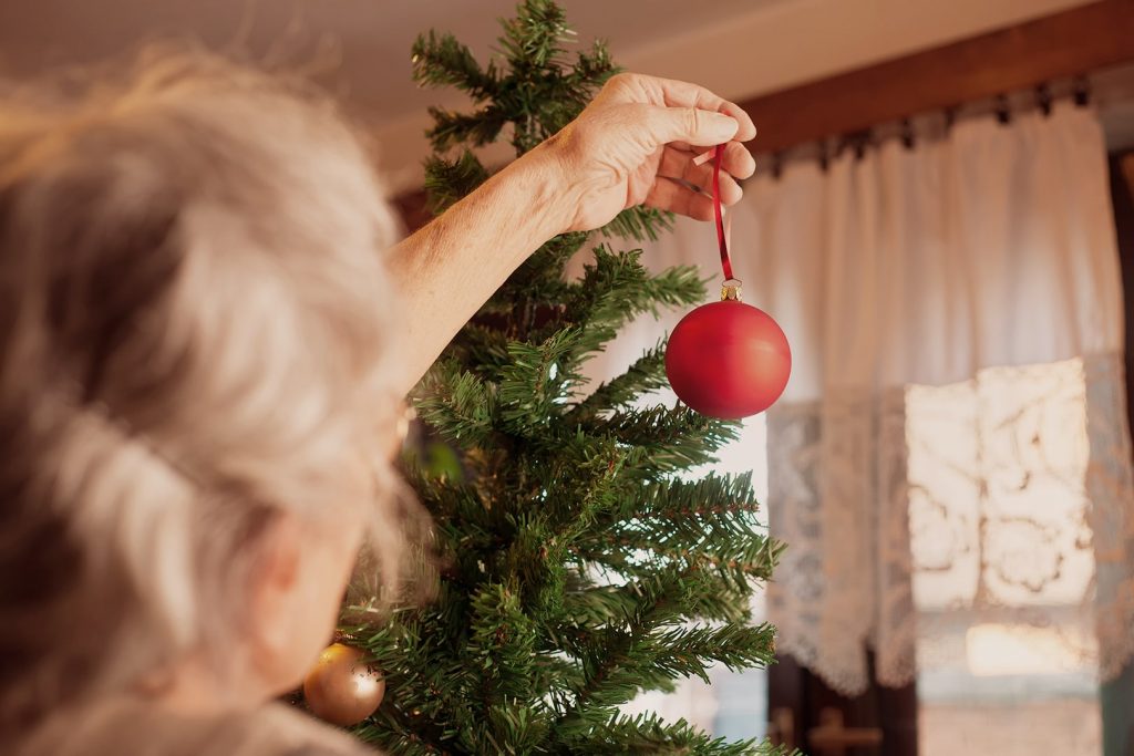Photo d'une boule de Noël rouge vive tenue par une aînée.