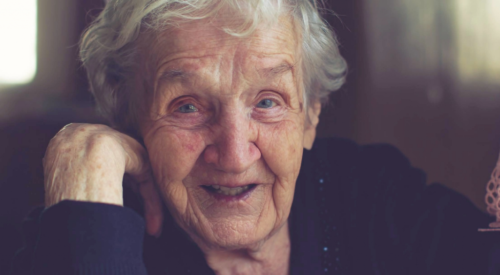 Close-up portrait of a charming elderly woman staring in the camera and smiling.