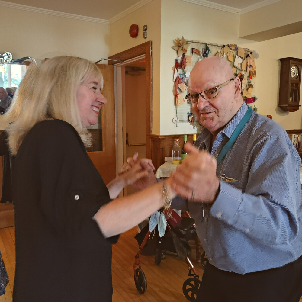 An elderly man dancing with a younger woman.