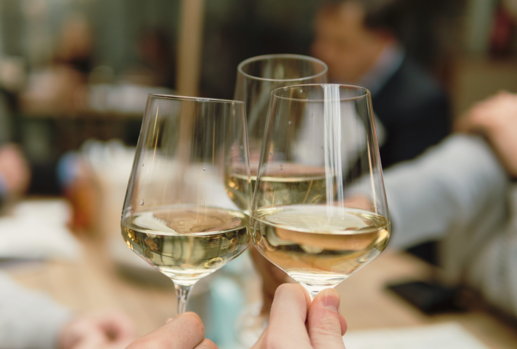 Three glasses of white wine touching during a toast.