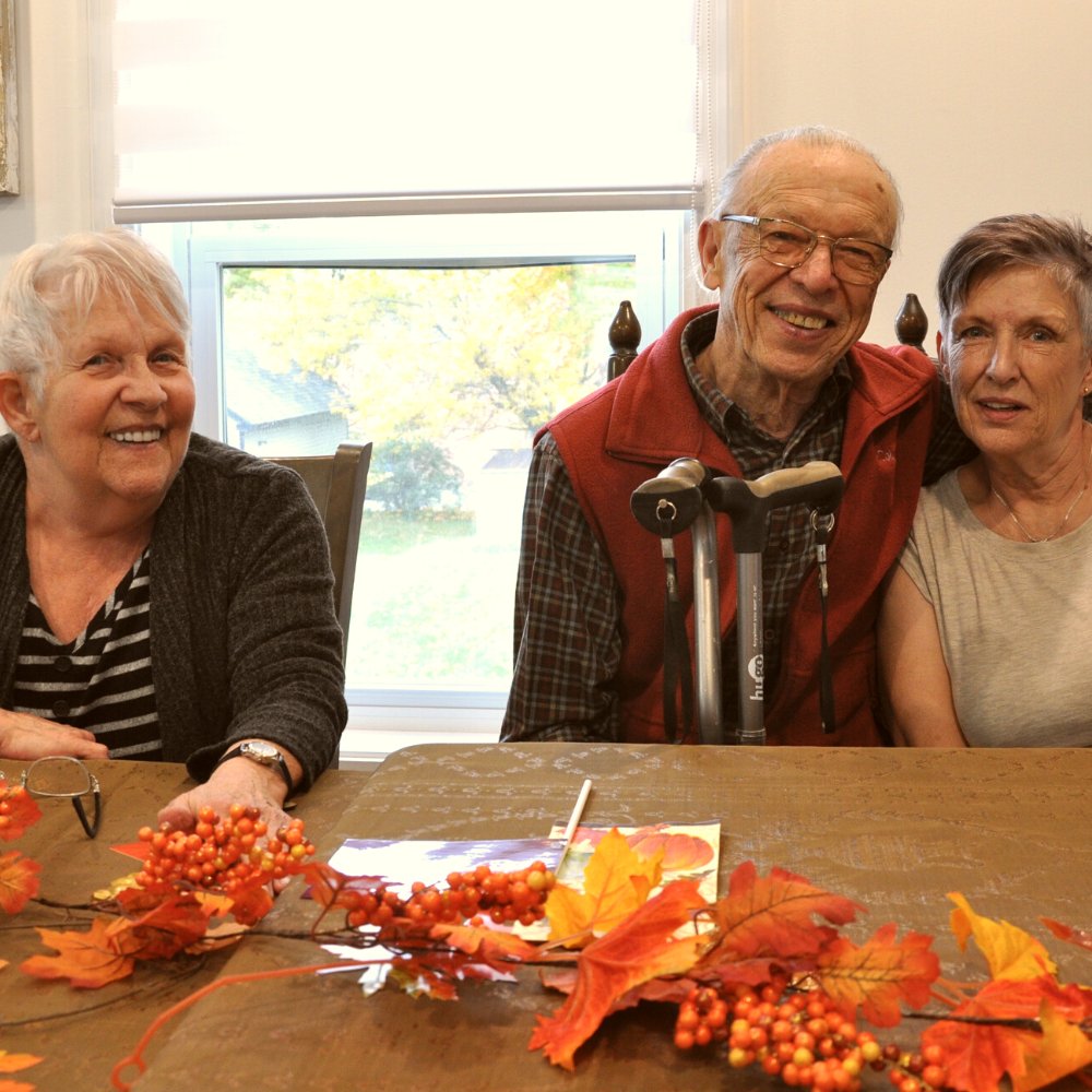 Photo of three smiling elders sitting at a table.