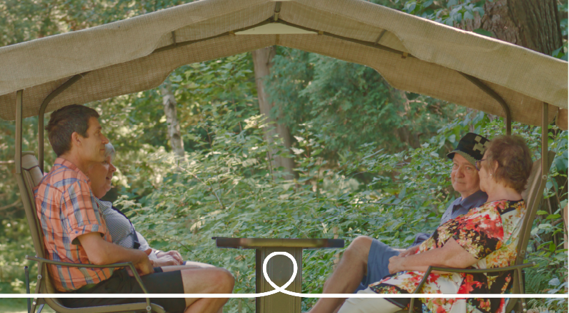 Couverture du rapport annuel 2023-2024 des Petits Frères. Des Grands Amis et un bénévoles s'ont assis paisiblement sur une balançoire véranda