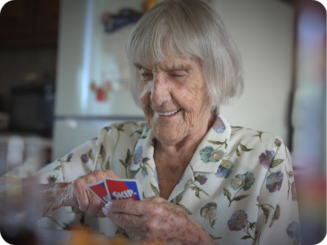 Dame qui joue aux cartes en souriant