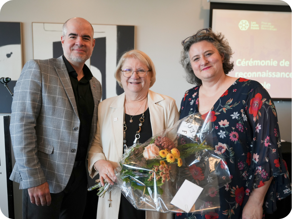 3 personnes qui regardent la caméra dont une dame avec des fleurs à la main