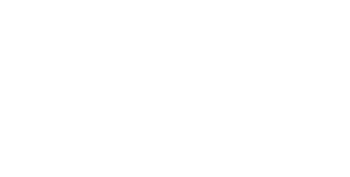 Une bénévole et sa Grande Amie, une personne aînée qu’elle accompagne, sont assises côte à côte dans le salon de cette dernière, souriantes et regardant vers la caméra, illustrant une relation de proximité, de confiance et de chaleur humaine.